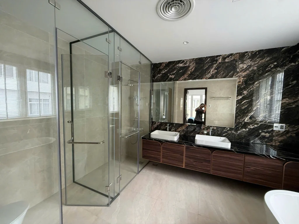 Phòng tắm biệt thự Sala Thủ Thiêm với vách kính cường lực và bồn rửa đôi hiện đại