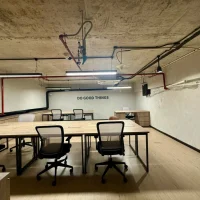 Không gian làm việc mở tại shophouse khối đế Sarica với bàn ghế văn phòng, trần bê tông và hệ thống kỹ thuật lộ thiên. Ảnh được cung cấp bởi Địa Ốc Sala Thủ Thiêm.